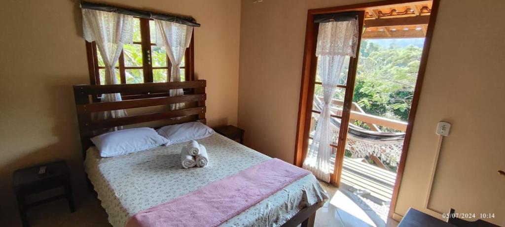 a teddy bear sitting on a bed in a bedroom with a window at Pousada Luar da Serra Lumiar in Nova Friburgo