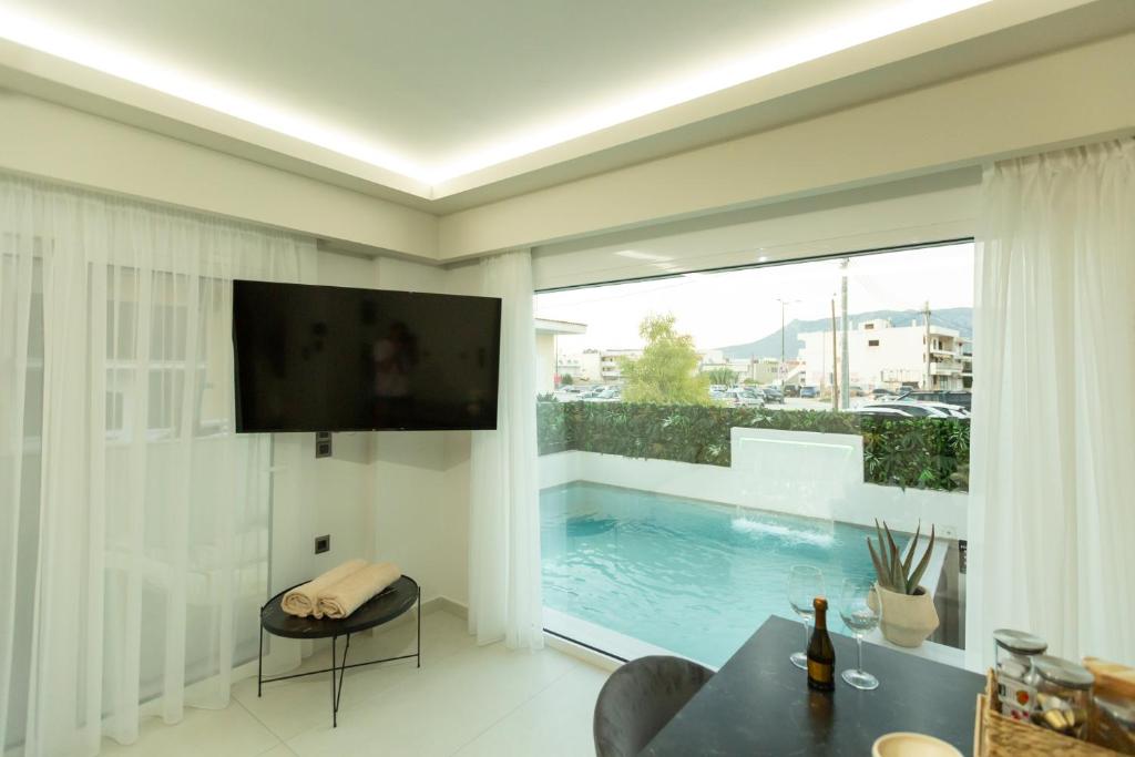 a living room with a tv and a swimming pool at BEQUEST Gold Luxury suites in Korinthos