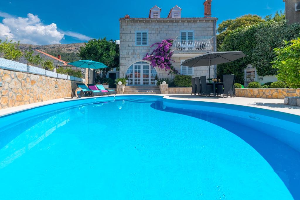 a large blue swimming pool in front of a house at Villa Ida in Dubrovnik