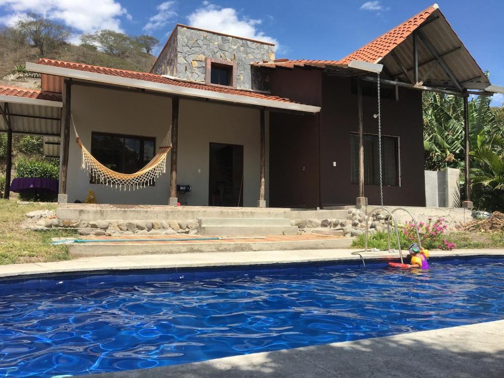 a house with a swimming pool in front of a house at Quinta Vacacional Yunguilla, Santa Isabel, Azuay in Santa Isabel