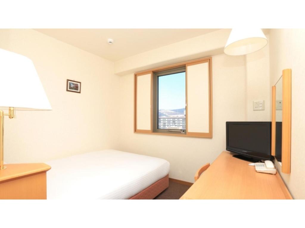 a bedroom with a bed and a desk with a television at Smile Hotel Nara - Vacation STAY 73673v in Nara