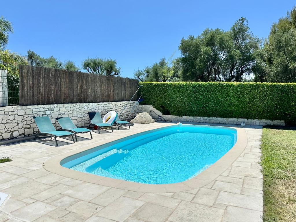 une piscine avec deux chaises et un mur en pierre dans l'établissement Magnifique studio, piscine, parking Nice, à Nice