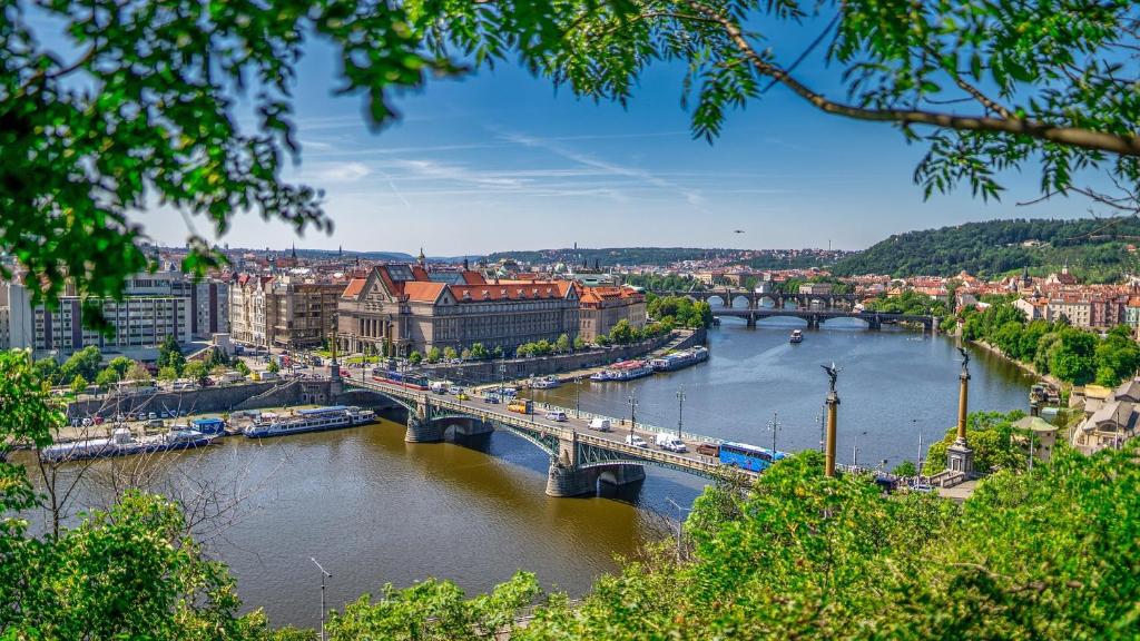 a view of a river with a bridge and buildings at Ubytování E4 Praha Letná in Prague