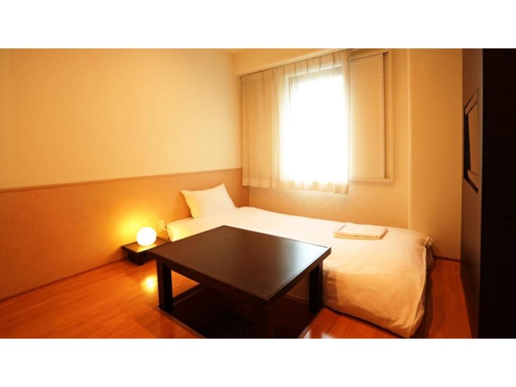 川口市にあるSmile Hotel Kawaguchi - Vacation STAY 76818vのベッドとテーブルのある小さな部屋