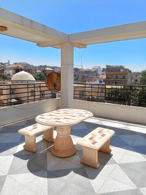 a patio with a table and benches on a balcony at Cléopâtre épouse de juba II in Tefeschoun