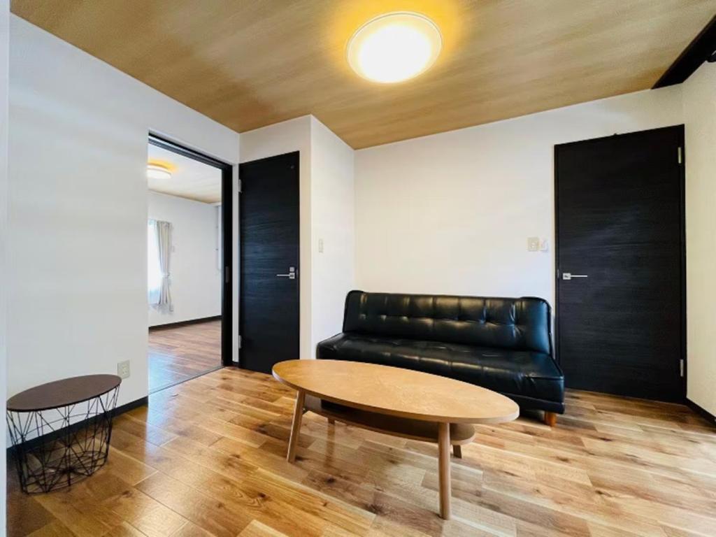 a living room with a black leather couch and a table at Sakura Kan - Vacation STAY 19678 in Sapporo