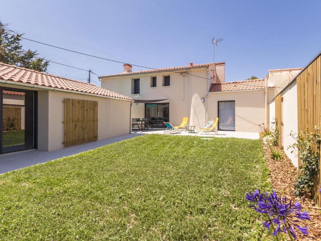 un patio trasero con césped frente a una casa en Gîte rénové proche plages, parking, jardin privatif, terrasse sud-est - FR-1-306-1315, en Machecoul