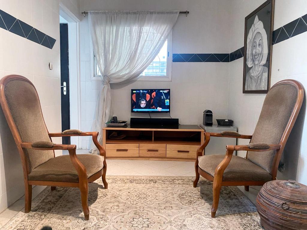 a living room with two chairs and a television at Touty in Dakan