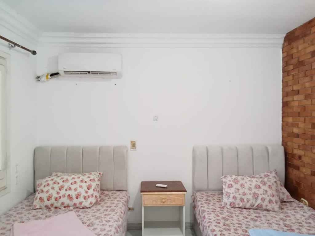 2 Betten in einem Zimmer mit einem Nachttisch und einem Tisch in der Unterkunft chalet1 ch21 with a wonderful view 2 bed rooms terrace and garden green beach in El-Alamein