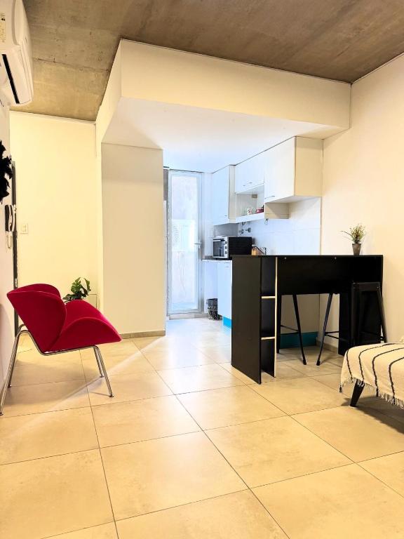 a living room with a red chair and a piano at Alem Apartamento in La Porteña