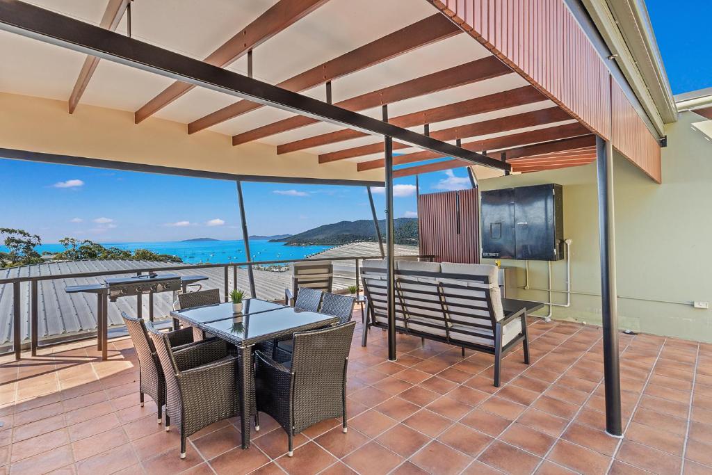 a patio with a table and chairs and a screen at Whiskey on Orana in Airlie Beach