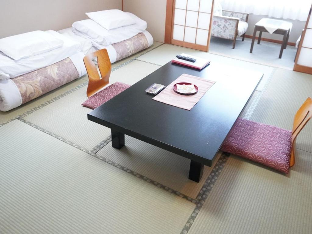 un salon avec une table et un lit dans l'établissement Yamaichi, à Shizukuishi 59 autres photos