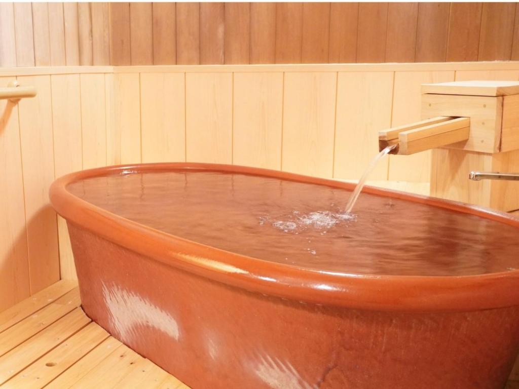 une baignoire en cuivre avec un robinet rempli d'eau dans l'établissement Yamaichi, à Shizukuishi