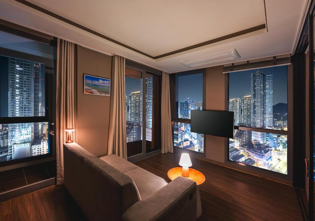 a room with a couch and a tv in a building at Elmomento Haeundae in Busan