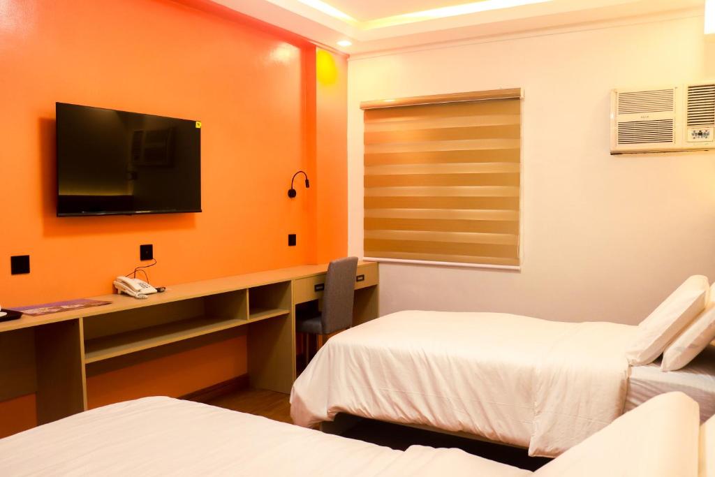 a room with two beds and a desk with a television at YMCA Makati in Manila