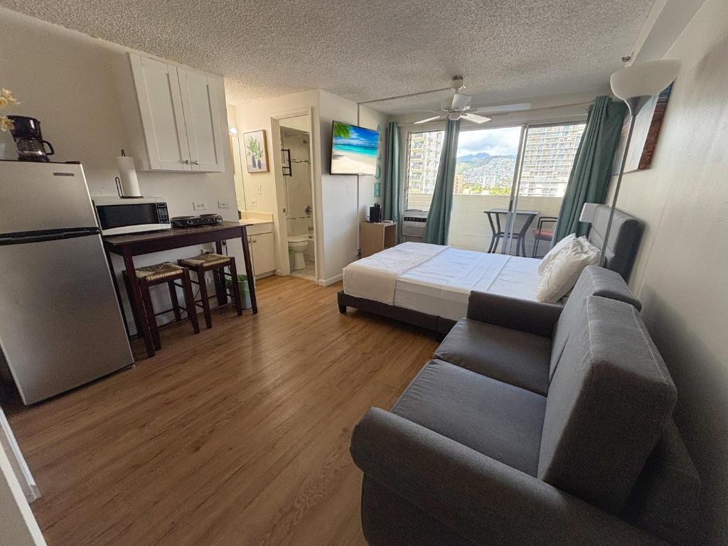 a living room with a couch and a kitchen at Mellow Kuhio Village Studio condo in Honolulu