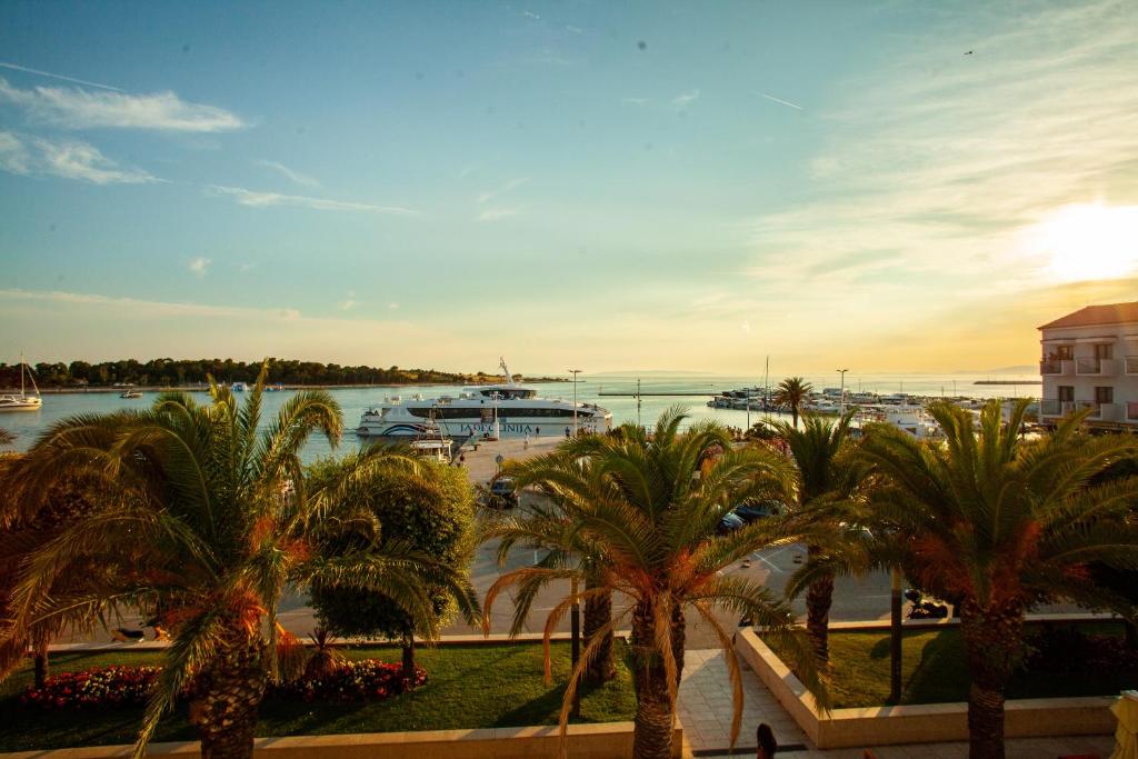 a view of a harbor with palm trees and boats at Portunata Penthouse - Novalja Center in Novalja