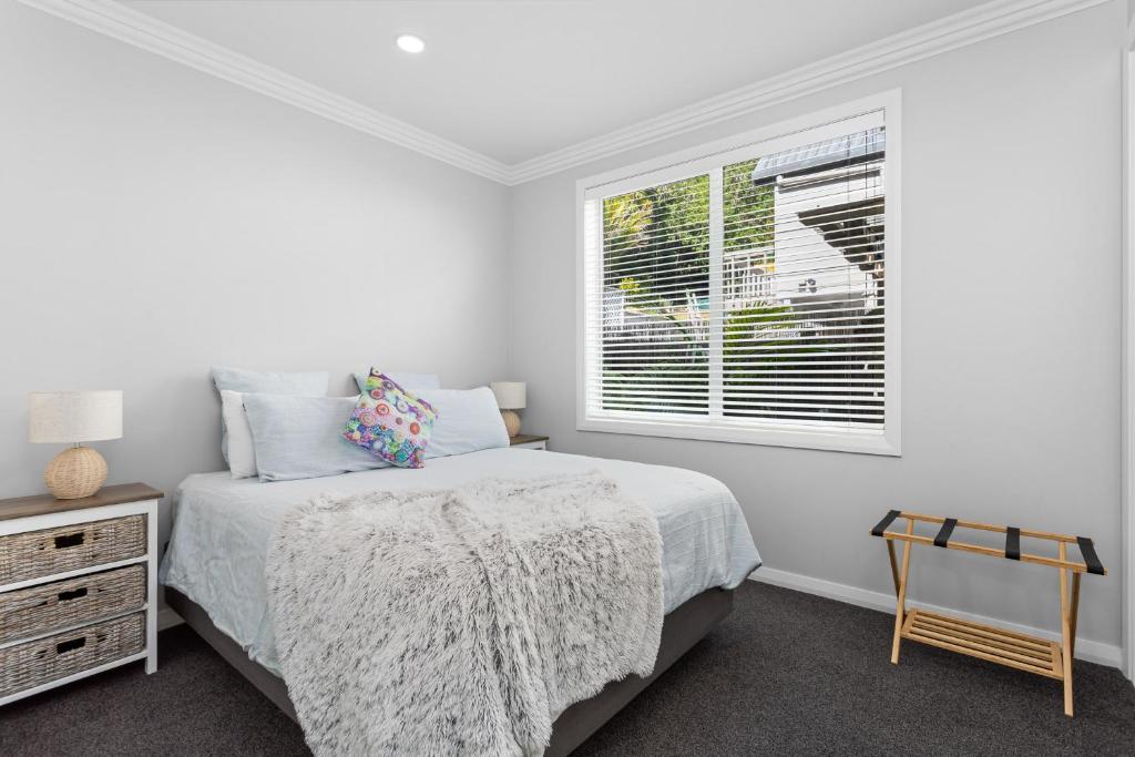 a white bedroom with a bed and a window at The Weiti Waterfront in Whangaparaoa