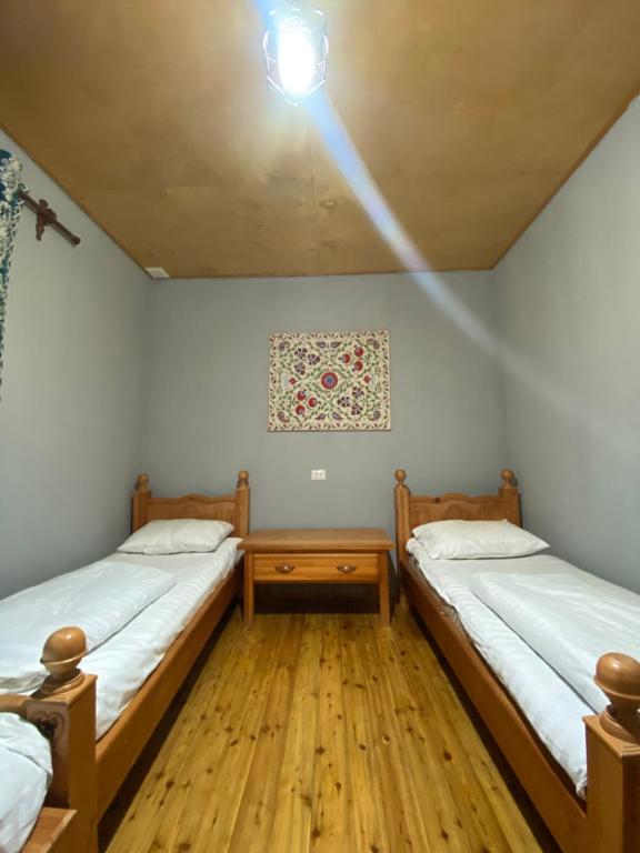 Dos camas en una habitación con suelo de madera. en NURATA MOUNTAIN GUESTHOUSE Shiringul, en Yukary-Ukhum