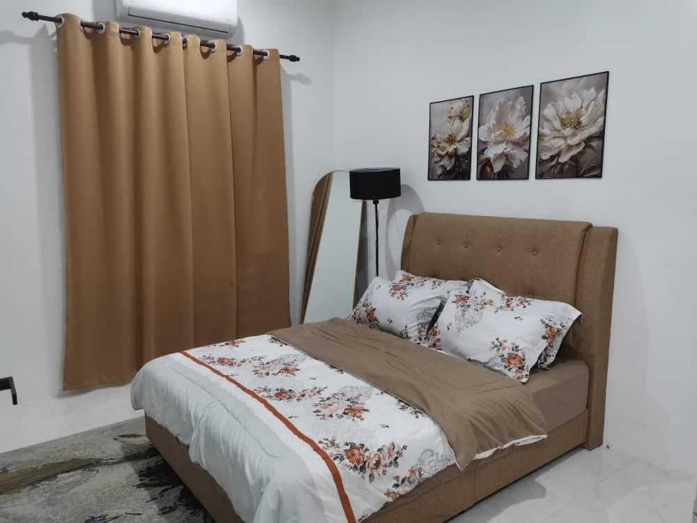 a bedroom with a bed with a curtain and pillows at Maldira Homestay in Batu Gajah in Gua Sai