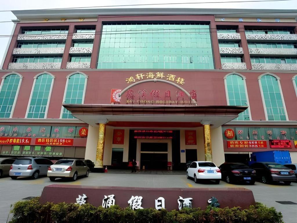 a large building with cars parked in front of it at Kui Chong Holiday Hotel in Shenzhen
