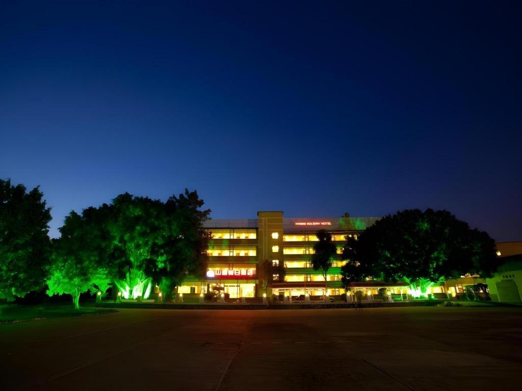 a lit up building with trees in front of it at Nanning Hawks Holiday Hotel in Nanning