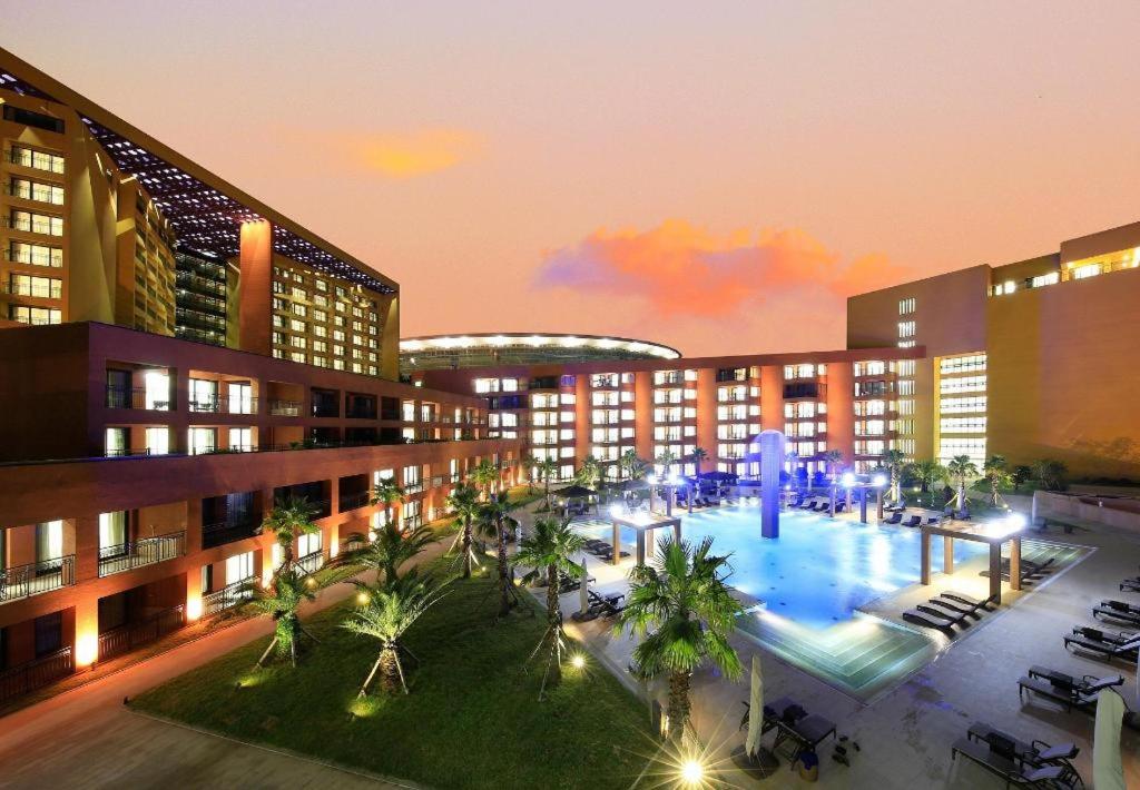 ein Hotel mit einem Pool, Palmen und Gebäuden in der Unterkunft Jeju Booyoung Hotel in Seogwipo