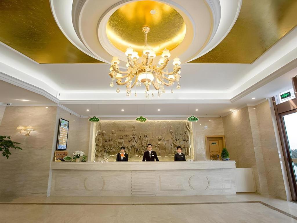 two people standing at a counter in a hotel lobby at Vienna Suzhou Oriental Gate Jinji Lake in Suzhou