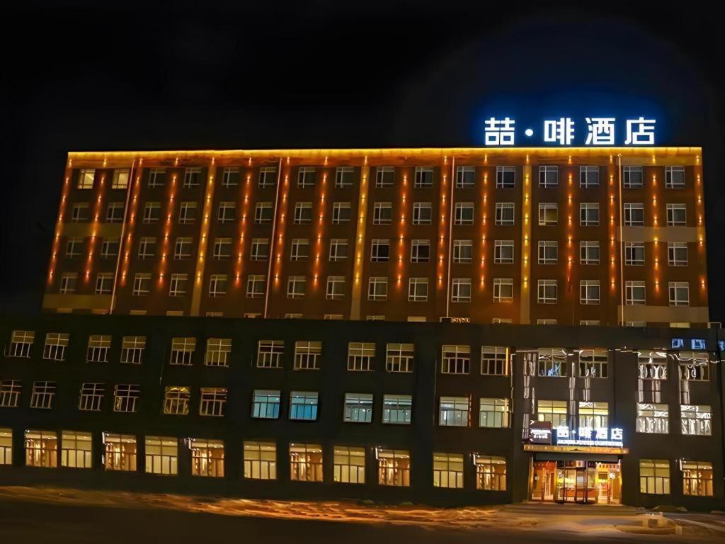 a large building with lights on it at night at James Joyce Coffetel·Changchun Railway Station in Changchun