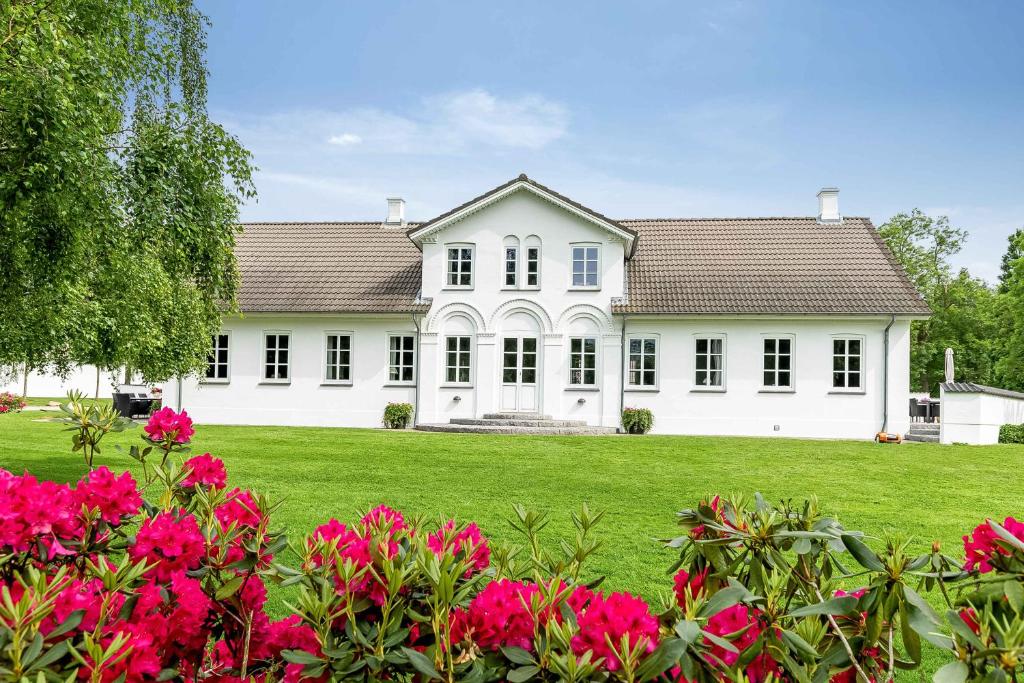 una casa bianca con fiori rosa nel cortile di Spacious House With Room For Relaxation And Play a Brenderup