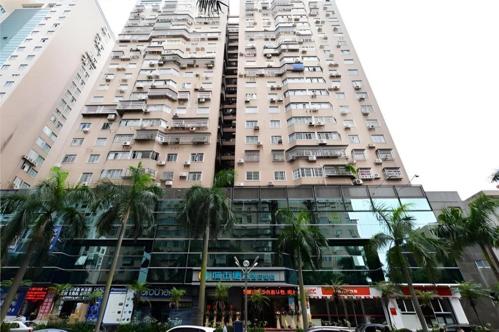 a tall building with palm trees in front of it at City Comfort Inn Zhuhai Qinglv Middle Road Riyuebei Grand Theater in Zhuhai