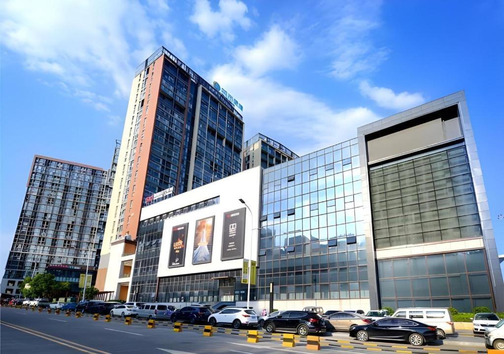 a large building with cars parked in a parking lot at City Comfort Inn Guiyang North High Speed Railway Station in Guiyang