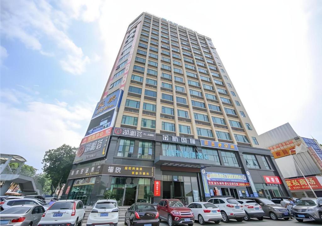 City Comfort Inn Dongguan Tangxia Garden Street في دونغقوان: مبنى شاهق به سيارات متوقفة في موقف السيارات