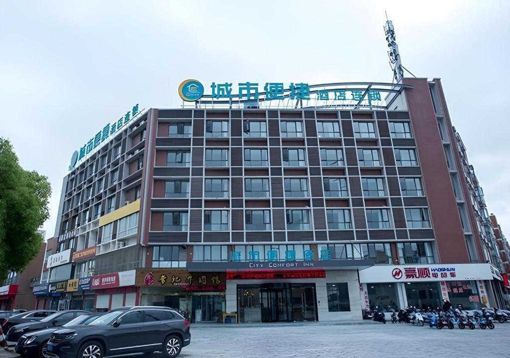 un grand bâtiment avec des voitures garées devant dans l'établissement City Comfort Inn Taizhou Wanda Plaza, à Taizhou