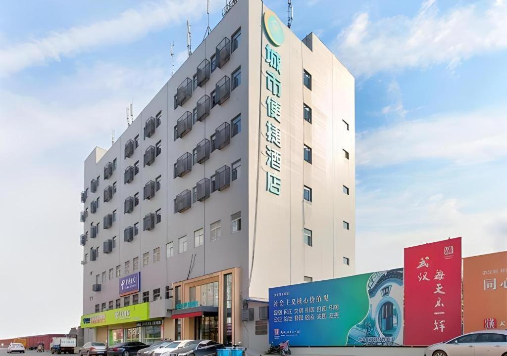 a large building with cars parked in front of it at City Comfort Inn Wuhan International Expo Center Qianjin Village Metro Station in Wuhan