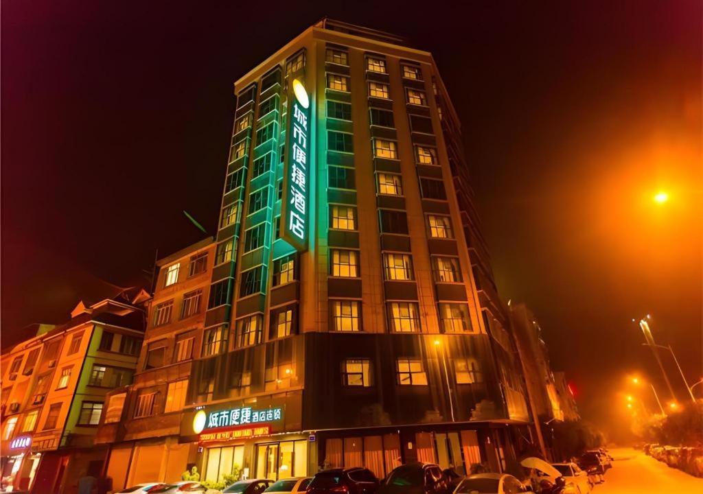 un grand bâtiment avec un panneau vert dans l'établissement City Comfort Inn Hechi Yizhou Erqiao, à Qingyuan