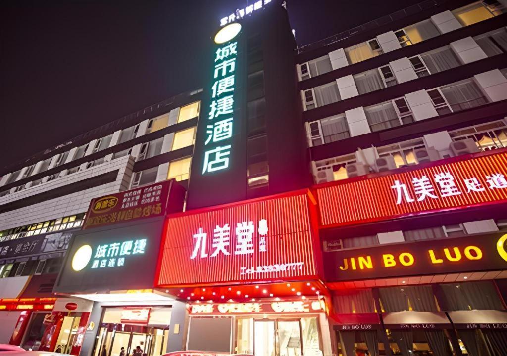 un bâtiment avec des enseignes au néon devant dans l'établissement City Comfort Inn Nantong Qidong Renmin Zhong Road Xingfudao, à Huilongzhen