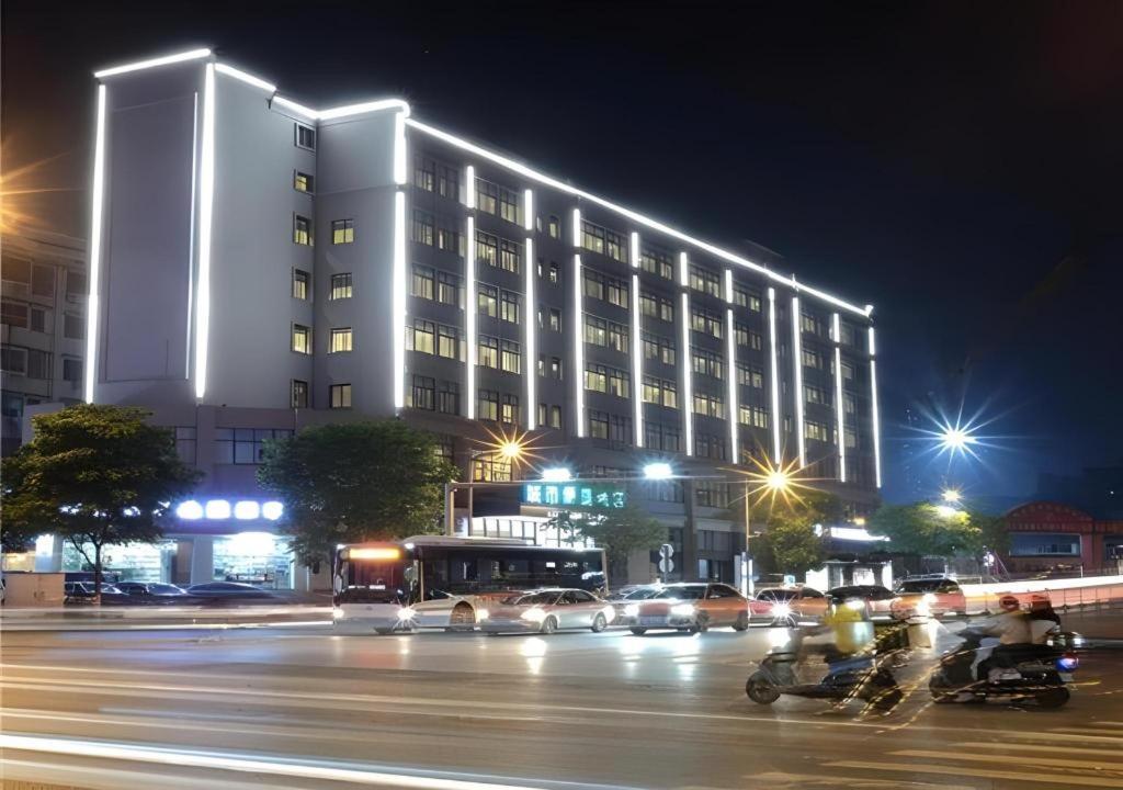 un edificio de noche con gente montando bicicletas delante de él en City Comfort Inn Changsha Railway Station Amiling Metro Station, en Changsha