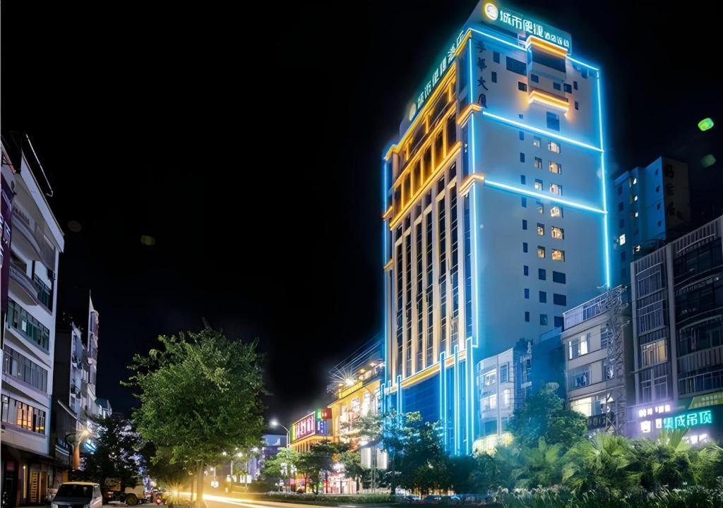 a tall building with blue lights on a city street at City Comfort Inn Maoming Xinyi Donghuicheng in Xinyi