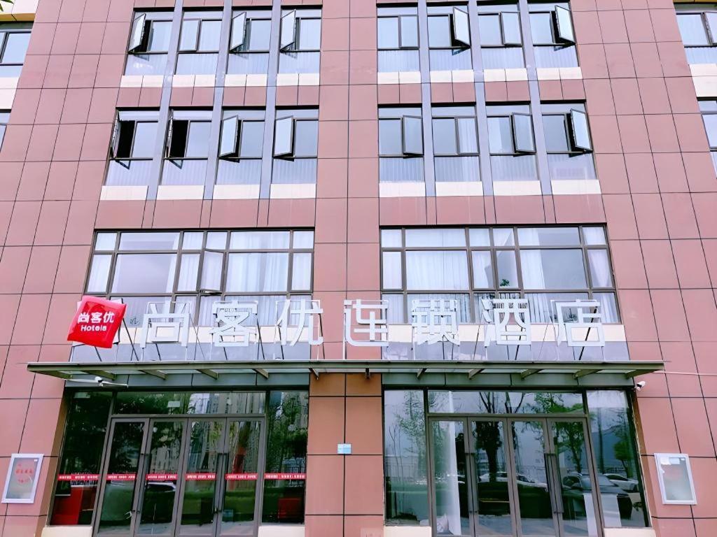 un bâtiment rose avec un panneau à l'avant dans l'établissement Thank Inn Hotel Yunnan Kunming Wuhua Puhuiyuan, à Kunming