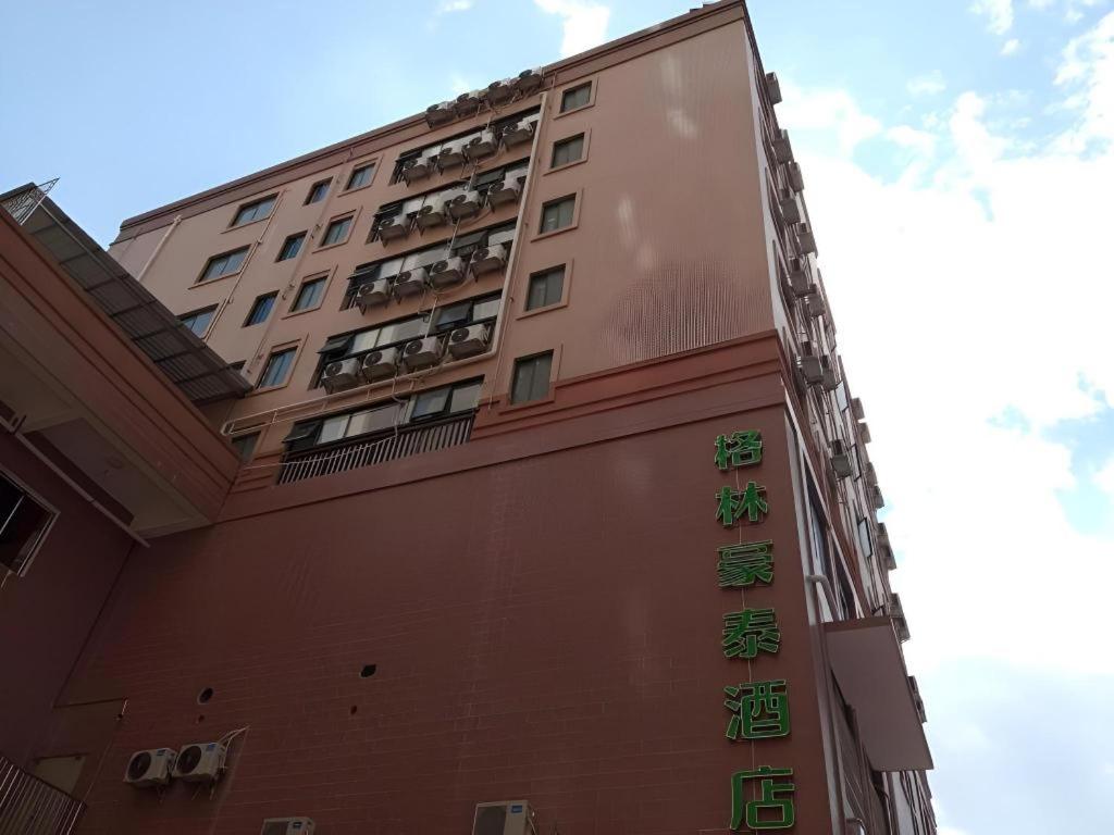 a tall building with green signs on the side of it at Green Tree Inn Guangxi Wuzhou 2nd Xinxing Road Liangguang Market in Wuzhou