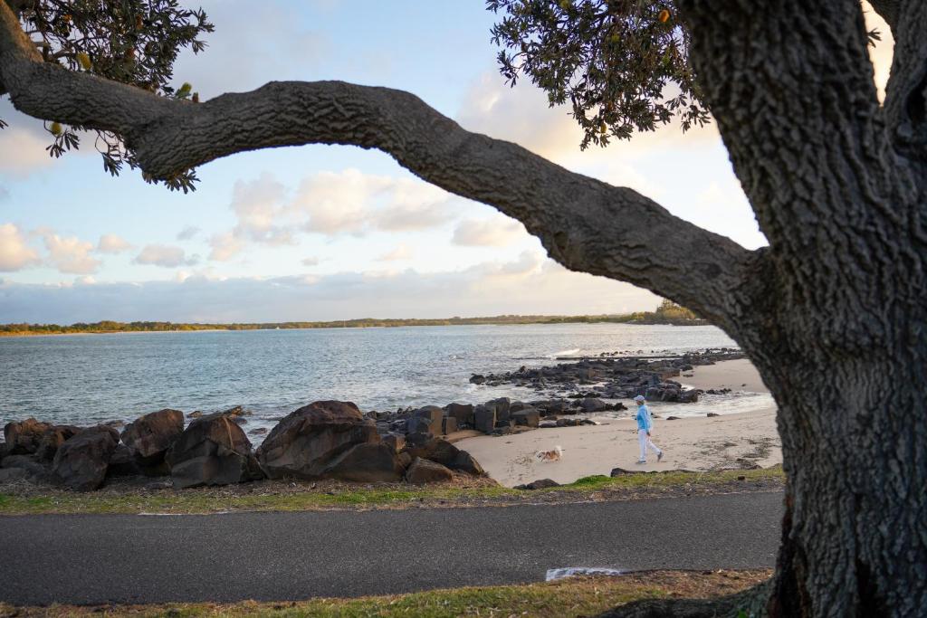 a person walking on the beach near the water at Reflections Shaws Bay - Holiday Park in Ballina