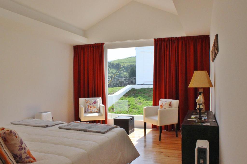 a bedroom with a bed and a large window at Aldeia do Priolo in Nordeste