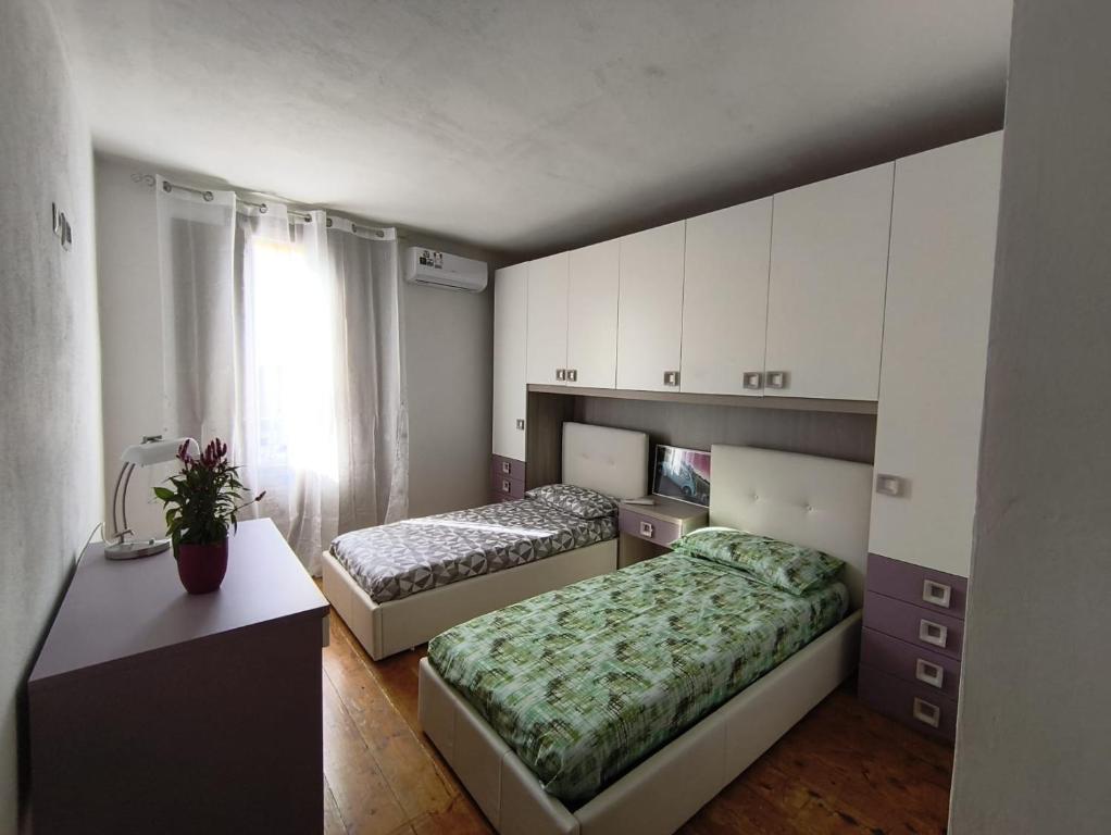 a bedroom with two beds and a desk and a window at Da Nonnu in Teulada