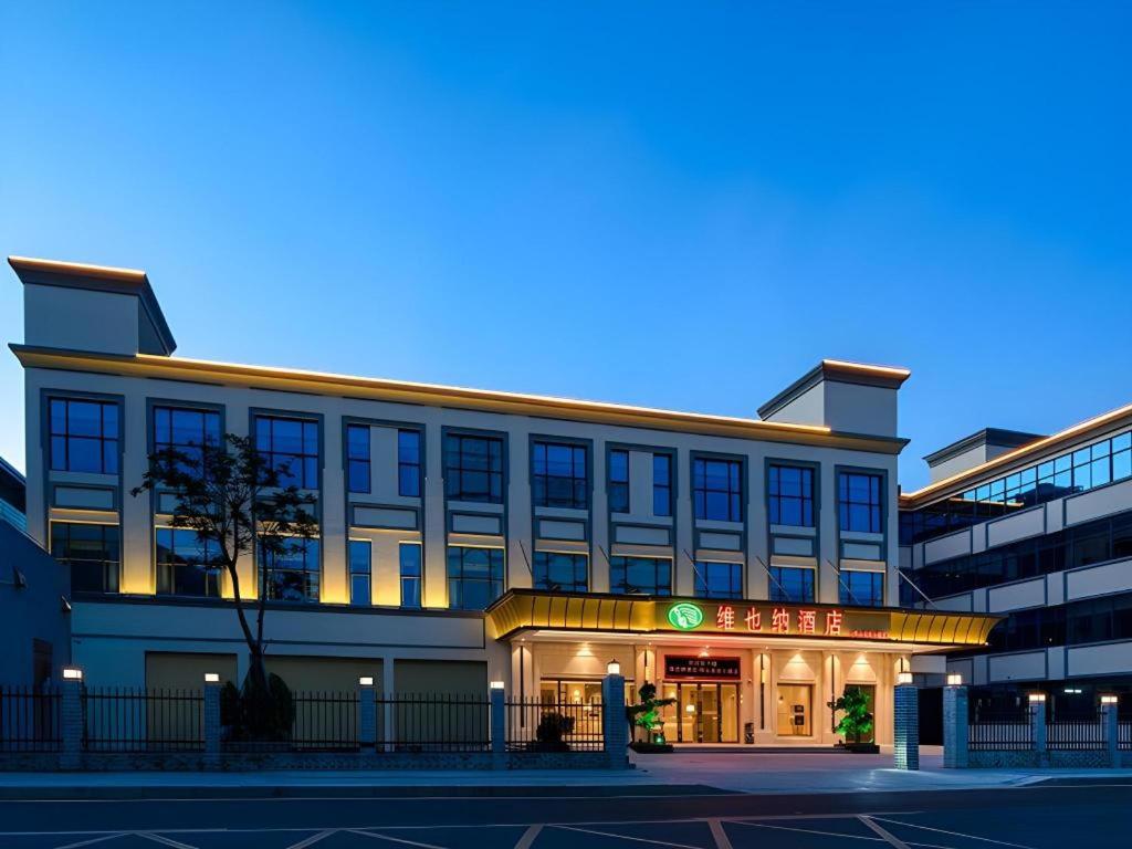 un grand bâtiment avec une enseigne devant dans l'établissement Vienna Hotel Shenzhen Pingshan Longtian Town, à Shenzhen