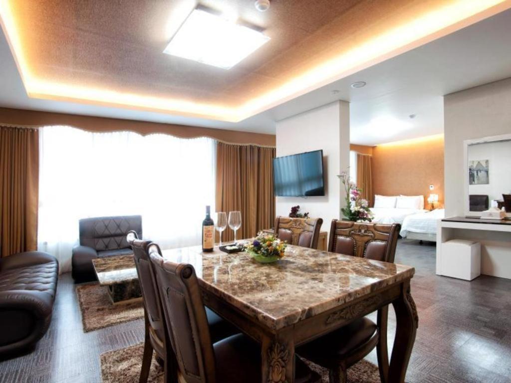 a living room with a dining table and a bedroom at BENIKEA Technovalley Hotel in Daejeon