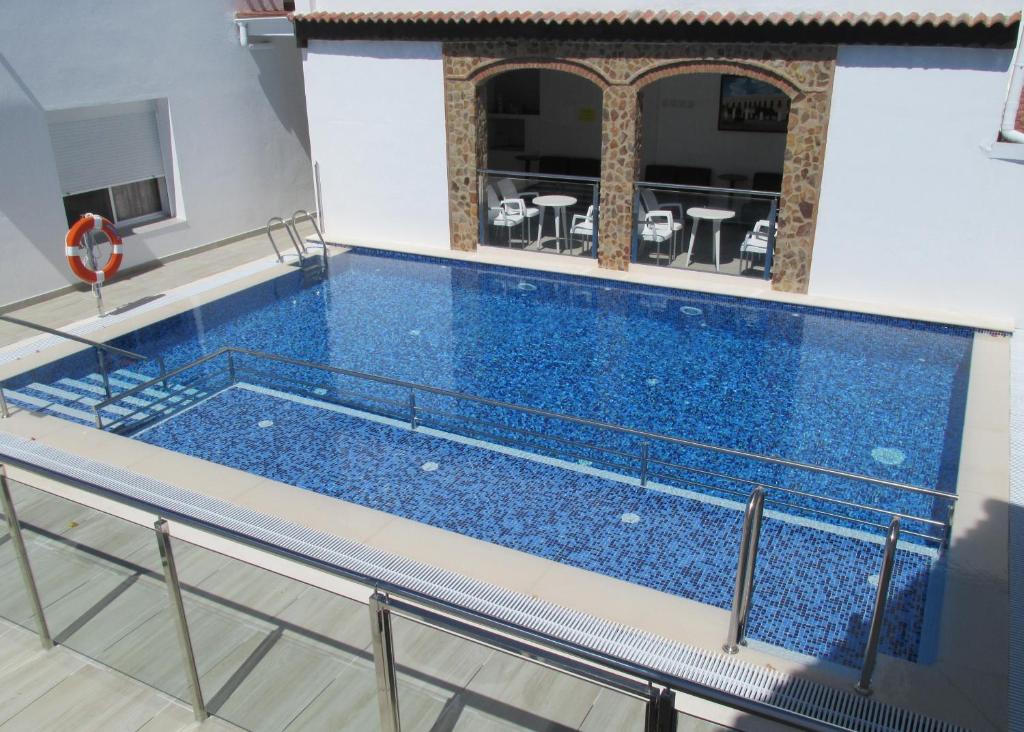 een groot zwembad met blauw water in een gebouw bij Apartamentos Trinidad in Alange