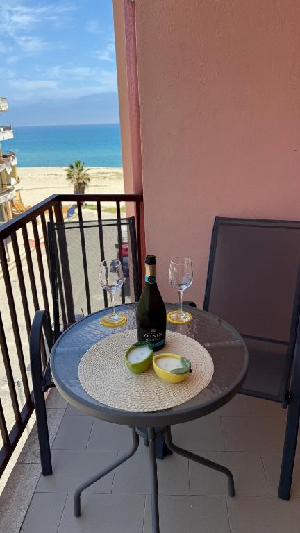 a table with glasses and a bottle of wine on a balcony at O forse il mare apartamento in Marina di Strongoli