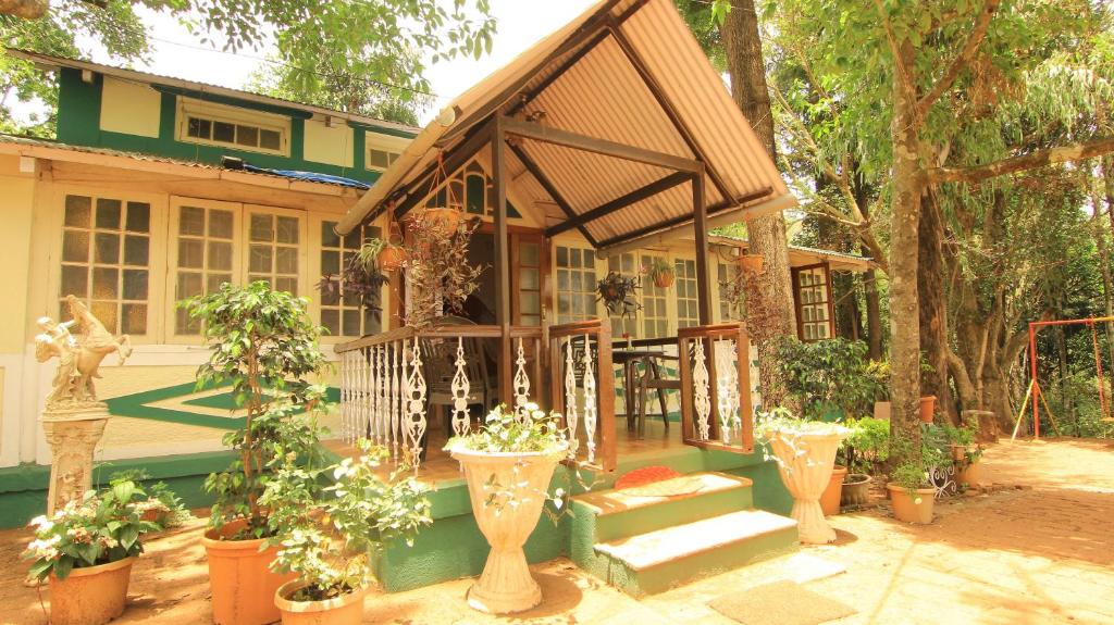 a green house with a porch with potted plants at Hotel Mount View Heritage in Panchgani