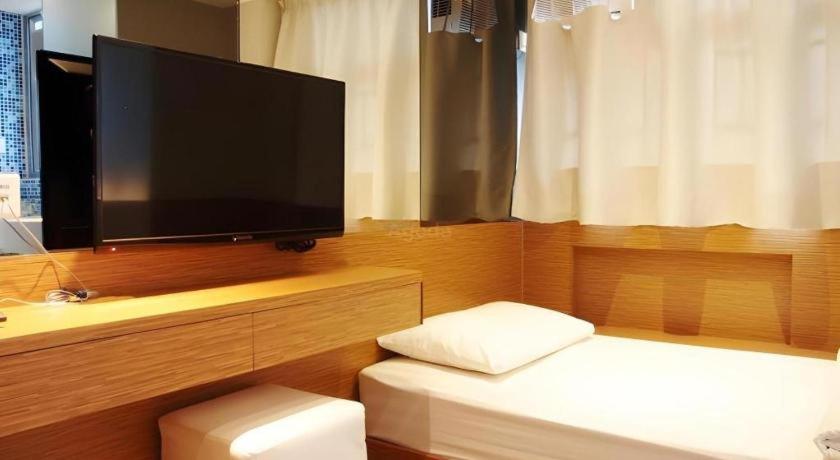 un soggiorno con TV e un letto con divano di Acesite Knutsford Hotel a Hong Kong